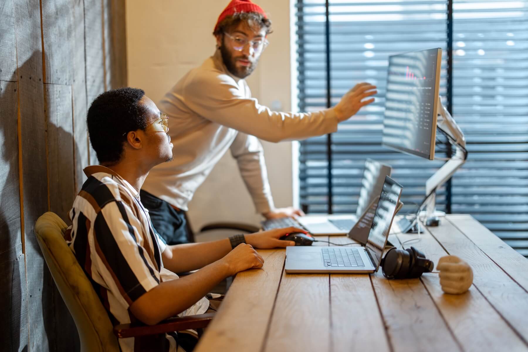 Two men working on a computer in an office at a distillery and analyzing compliance management ROI