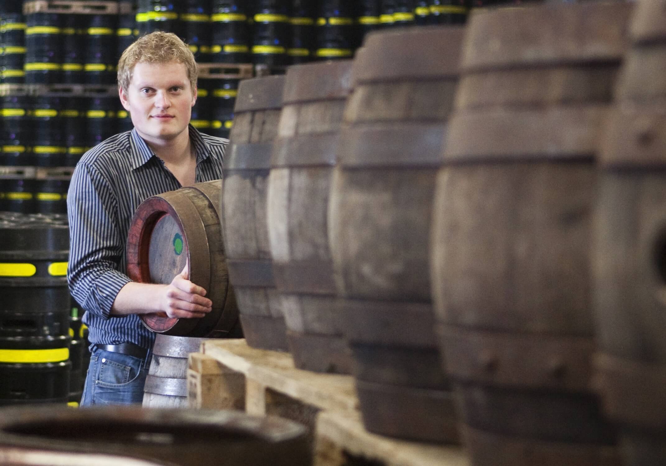 A man moving barrels at a whiskey distillery